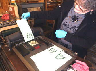 Deborah Holcomb pulls the first proof of
                her wood engraving - on the smaller Showcard/Vandercook
                sign/proof press